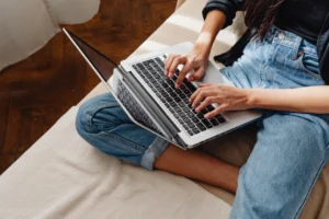 Fashion designer sitting on bed working on laptop